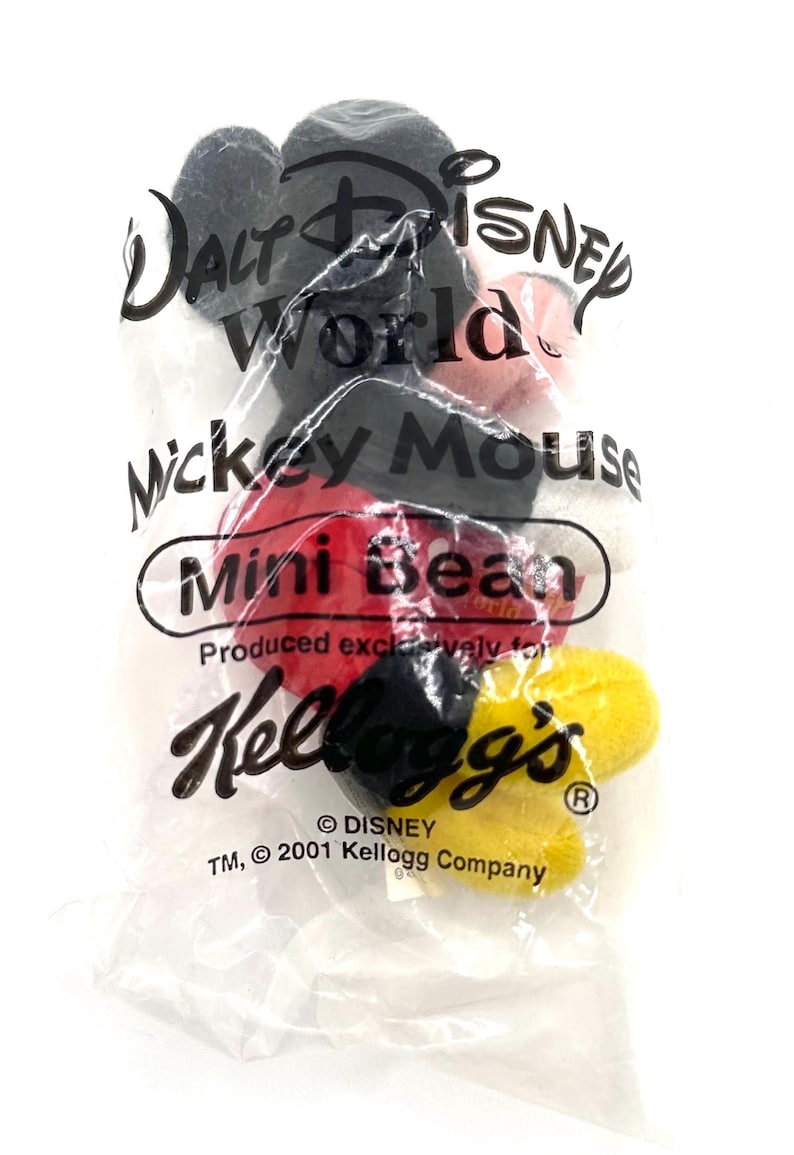 Pu&ograve; includere: Un sacchetto di plastica trasparente contenente mini caramelle a forma di Mickey Mouse. La borsa presenta il logo Walt Disney World, il testo "Mickey Mouse" e il logo Kellogg's. Le caramelle sono rosse, nere e gialle.