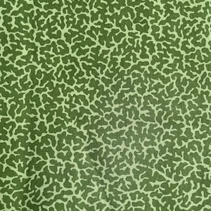 May include: Close-up of green fabric featuring a repeating pattern of light green, organic shapes, similar to coral or branching structures. The design creates a textured effect, suitable for textile applications.
