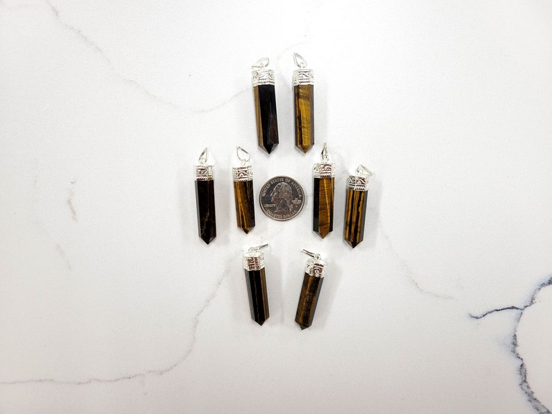 May include: Ten tiger's eye gemstone pendants with silver caps. The pendants are arranged in a star shape with a US quarter for scale.