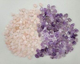 Puede incluir: Una colección de piedras de cuarzo rosa y amatista pulidas. Las piedras son de color rosa claro y morado y están dispuestas en forma de semicírculo.