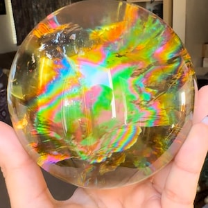 Könnte beinhalten: Eine klare Kristallkugel mit schillernden Regenbogenfarben, die ein Lichtspektrum zeigt.