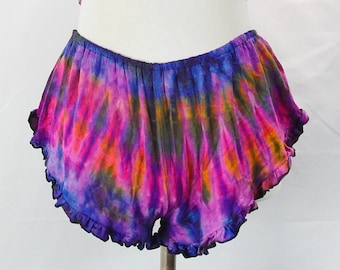 May include: A tie-dye print set with a halter top and ruffled shorts. The top has a ring detail at the center. The set is in shades of pink, purple, blue, and orange.