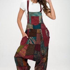 Może przedstawiać: Komplet jednoczęściowy w stylu patchwork z różnymi kolorami i wzorami, w tym czerwony, brązowy, zielony i niebieski. Komplet ma szerokie nogawki i luźny krój.