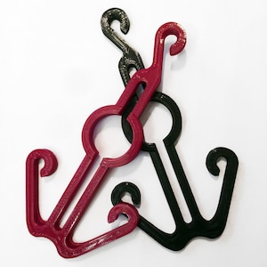 May include: Two plastic hooks, one red and one black, are intertwined. The hooks have a rounded loop at the top and two prongs at the bottom.