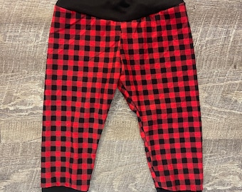 Op de afbeelding: Rode en zwarte geruite leggings met een zwarte tailleband en boorden.