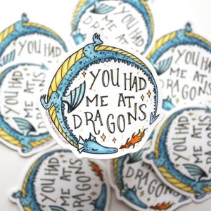 Op de afbeelding: Een sticker met een blauwe en gele draak en de tekst "You had me at dragons".