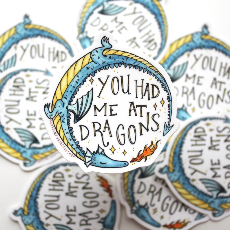 Op de afbeelding: Een sticker met een blauwe en gele draak en de tekst "You had me at dragons".
