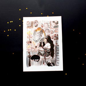 May include: A woman with long dark hair sits at a vanity with three black cats. The vanity is decorated with candles, a mirror, and framed pictures. The woman is wearing a long, flowing dress.