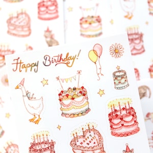 May include: Sheet of stickers with a watercolor design featuring birthday cakes, balloons, stars, and a goose wearing a party hat. The words "Happy Birthday!" are written in a decorative font.