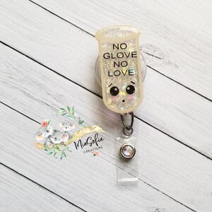 May include: A white glitter badge holder with a cartoon face and the text "NO GLOVE NO LOVE".