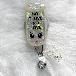 May include: A clear, glitter-filled badge reel with a cute cartoon face and the text "NO GLOVE NO LOVE". The reel is attached to a silver retractable badge holder with a clear plastic badge holder.