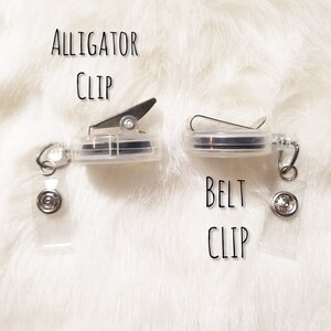 May include: Two clear plastic badge holders with metal clips. The holder on the left has an alligator clip and the holder on the right has a belt clip. Both holders have a clear plastic strap.