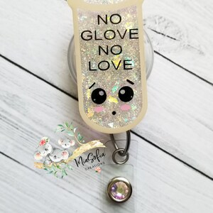 May include: A white glitter badge holder with a cartoon test tube design. The test tube has a face with eyes and blush. The text on the test tube reads "NO GLOVE NO LOVE". The badge holder has a clear plastic strap and a silver swivel clip.
