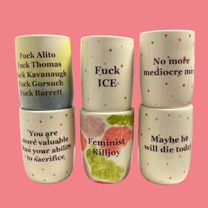 May include: Six ceramic mugs with various phrases and colorful polka dots. The mugs feature text such as "Fuck Alito," "Fuck ICE," and "Feminist Killjoy." The mugs are white with colorful accents and text.