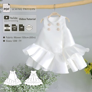 Könnte beinhalten: Ein weißes, ärmelloses Kleid mit einem Rüschen-Saum und einem doppelreihigen Knopfverschluss. Das Kleid hängt an einem Holzbügel. Das Kleid ist für ein Kind gedacht und es gibt ein YouTube-Video-Tutorial. Das Schnittmuster ist in den Größen 12 Monate bis 7 Jahre erhältlich und benötigt 150 cm (60 Zoll) gewebten Stoff.