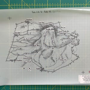 May include: A detailed black and white map of the Pendle Hill area, featuring place names like Downham, Barley, and Sabden. The map includes contour lines, roads, and the text "Pendle Hill". The map is on a translucent sheet.