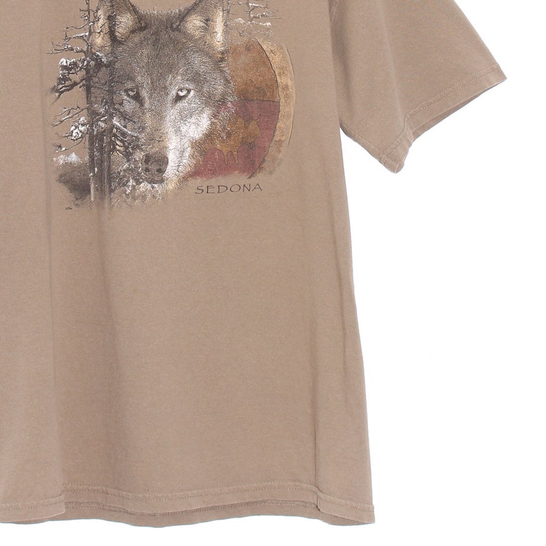 May include: A brown t-shirt with a wolf graphic and the text "SEDONA" printed on the front.