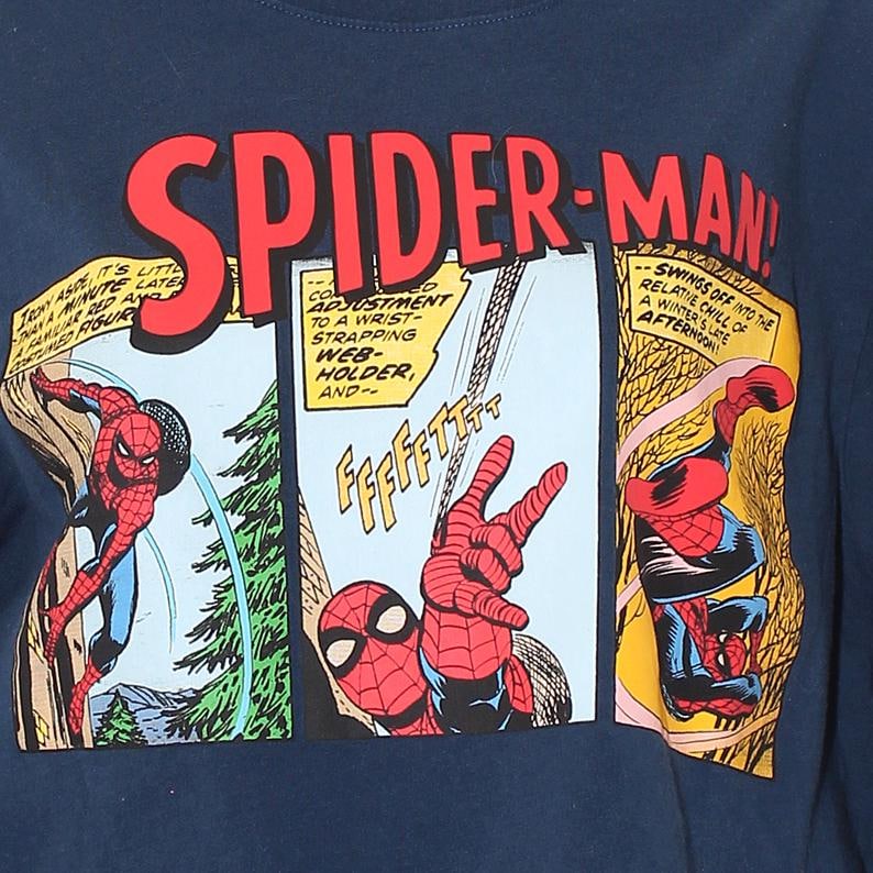 以下が含まれることがあります： ネイビーブルーのTシャツ。スパイダーマンと赤い文字で「SPIDER-MAN」と書かれたコミックデザイン。パネルには、吹き出しや効果音とともに、スパイダーマンがアクションを起こしている様子が描かれています。クラシックなスーパーヒーローをテーマにしたアパレルアイテム。