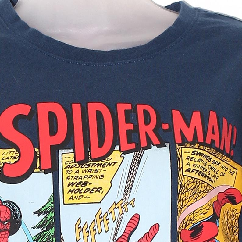 以下が含まれることがあります： ネイビーブルーのTシャツ。コミックパネルのデザインで、赤い文字で「SPIDER-MAN！」と書かれています。デザインには、コミックのテキストとスパイダーマンのイラストが含まれています。