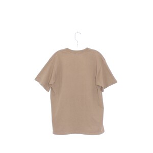 May include: A plain brown t-shirt hanging on a white hanger. The t-shirt has short sleeves and a crew neck.