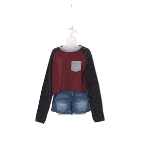 May include: A maroon and gray long-sleeved shirt with a gray pocket and denim shorts. The shirt has a gray neckline and dark gray sleeves. The denim shorts are a light blue wash.