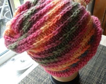 May include: A pink, orange and green striped knitted hat. The hat is made with a chunky yarn and has a slouchy fit.