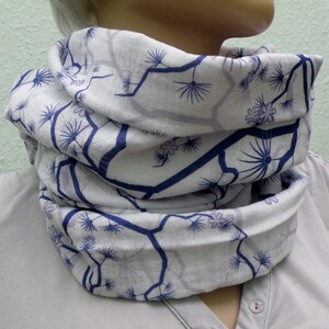 May include: A white infinity scarf with a blue and purple floral pattern. The scarf is made of a soft, lightweight fabric and is perfect for adding a touch of style to any outfit.