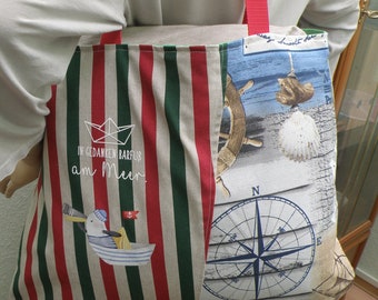 Może przedstawiać: Torebka typu shopper w paski z motywem marynistycznym. Torebka jest wykonana z płótna i ma czerwono-biało-zielone paski. Jest ozdobiona kompasem, kołem sterowym i muszlą. Na torebce wyszyty jest napis "In Gedanken Barfuß am Meer".