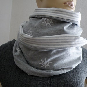 Könnte beinhalten: Ein grauer Infinity-Schal mit weißem Streifenbesatz und einem weißen Schiffsradmuster.