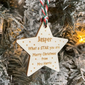 May include: A wooden star-shaped Christmas decoration with the name "Jasper" and the message "What a STAR you are Merry Christmas from Mrs Harris".