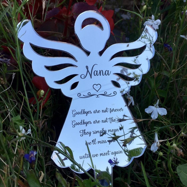 May include: A silver mirrored angel with cut-out wings and the word "Nana" inscribed on the front. The angel has a heart and a quote that reads "Goodbyes are not forever, Goodbyes are not the end, They simply mean we'll miss you until we meet again."