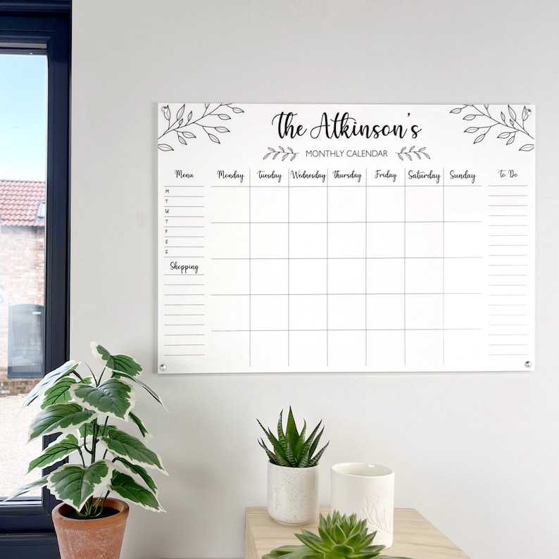 Shows a full view of our large personalised monthly planner mounted on the wall. 'The Atkinson's monthly calendar' is written at the top. Made by The Bespoke Workshop.