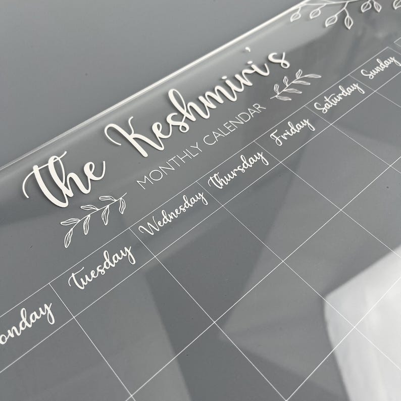Monthly Planner in clear acrylic with white cursive font. Made by The Bespoke Workshop.