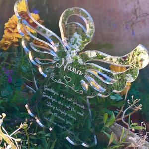 May include: A clear acrylic angel wing memorial with the name "Nana" and the quote "Goodbyes are not forever, Goodbyes are not the end, They simply mean we'll miss you until we meet again".