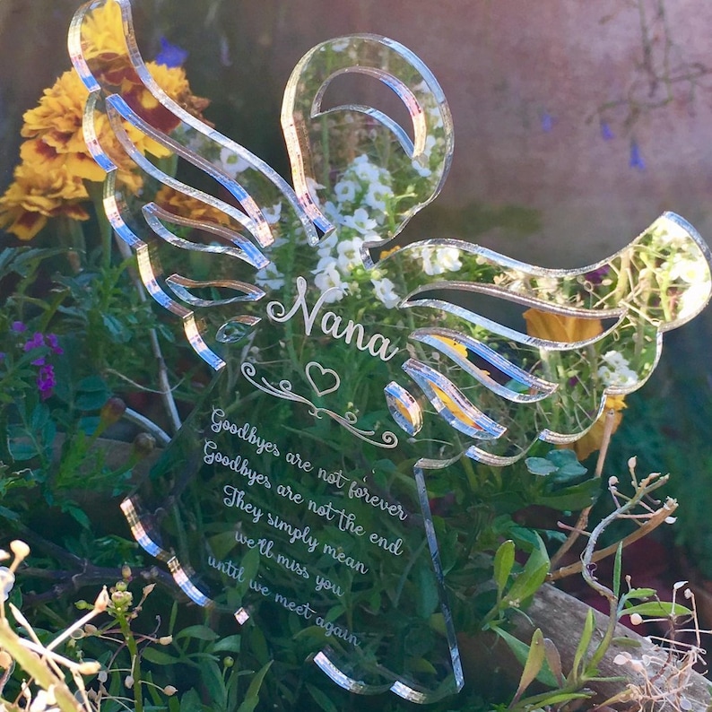 May include: A clear acrylic angel wing memorial with the name "Nana" and the quote "Goodbyes are not forever, Goodbyes are not the end, They simply mean we'll miss you until we meet again".