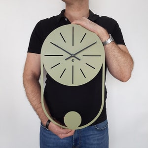 May include: A green and black wall clock with a round face and a pendulum design. The clock has a minimalist style with black hands and a black center.