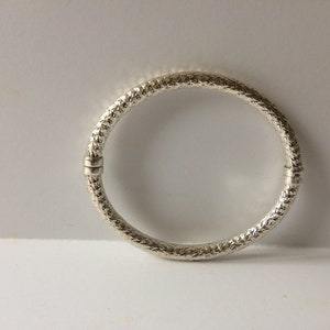 May include: A silver bangle bracelet with a textured design.