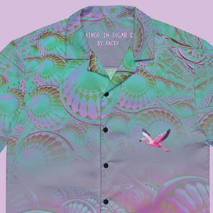 May include: Short-sleeved button-down shirt with a vibrant, surreal design. The shirt features a repeating pattern of abstract shapes in shades of teal, pink, and purple, with two pink flamingos. The text "Flamingo in Solar E by Kacix" is printed on the collar.