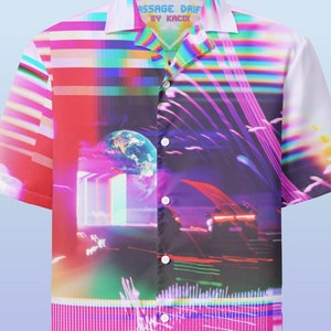 May include: A white short-sleeved button-down shirt with a colorful, abstract print. The print features a mix of geometric shapes, lines, and colors, including pink, blue, green, and yellow. The shirt has a collar and a button closure. The text "PASSAGE DRIFT BY KACK" is printed on the front of the shirt.