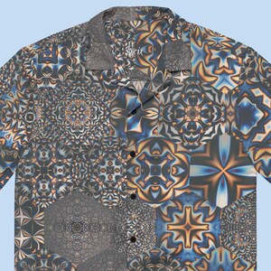 May include: Short-sleeved shirt with a geometric patchwork pattern in blue, grey, and orange. It has a camp collar and a button-up front. The word "Spirit" is printed on the collar. A stylish summer shirt.