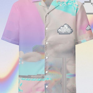 Può includere: Una camicia a maniche corte con bottoni e un design a nuvola pixelato in tonalità rosa, blu e grigio. La camicia ha una vestibilità rilassata e un colletto.