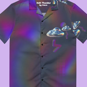 May include: A short-sleeved button-up shirt with a dark background and a holographic iridescent pattern. The shirt features a design of clouds and lightning bolts with a rainbow effect. The text "Soft Thunder by Kacic" is printed on the collar.