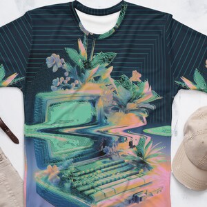 Puede incluir: Una camiseta azul y verde con una computadora retro y flores impresas en ella. La computadora est&aacute; rodeada por un efecto de glitch, pixelado.