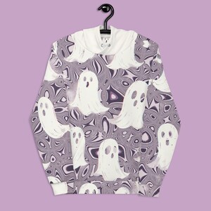 Puede incluir: Una sudadera con capucha blanca con un patr&oacute;n de remolinos p&uacute;rpura y blanco y siluetas de fantasmas blancas.