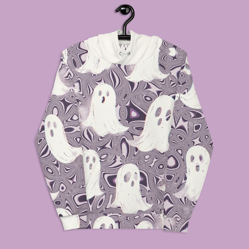 Puede incluir: Una sudadera con capucha blanca con un patr&oacute;n de remolinos p&uacute;rpura y blanco y siluetas de fantasmas blancas.