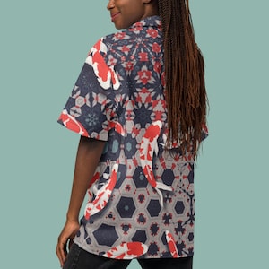 May include: Short-sleeved shirt with a koi carp pattern. The shirt has a navy blue background with red and white koi carp and geometric shapes. The shirt is worn by a person.