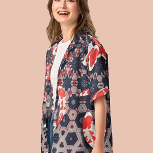 May include: A short-sleeved shirt with a koi carp design. The shirt has a navy blue background with red and white koi carp and geometric shapes. It is worn over a white t-shirt and blue jeans.