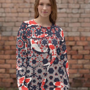 May include: Crew neck sweatshirt featuring a koi fish design. The pattern includes red, white, and blue koi fish against a dark blue and gray geometric background. The long-sleeved top is made of a soft material.