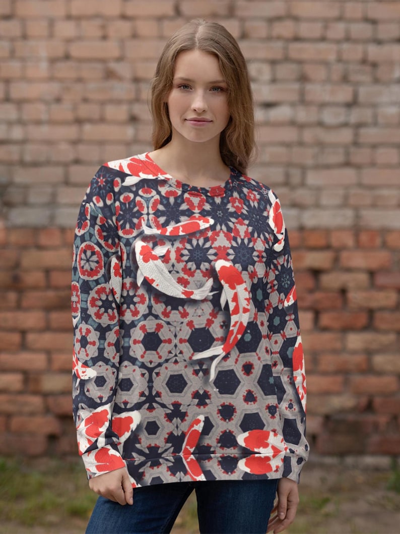 May include: Crew neck sweatshirt featuring a koi fish design. The pattern includes red, white, and blue koi fish against a dark blue and gray geometric background. The long-sleeved top is made of a soft material.
