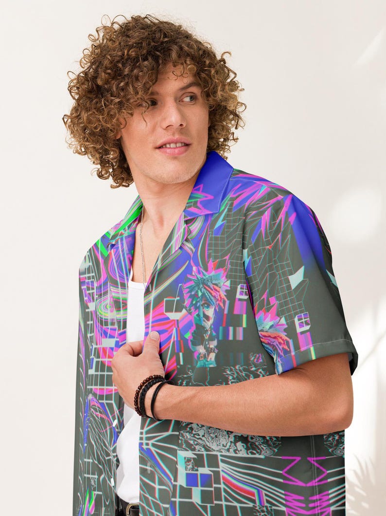 May include: A short-sleeved button-up shirt with a colorful, abstract print featuring geometric shapes, lines, and a pixelated figure. The shirt has a collar and a relaxed fit.